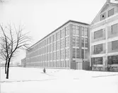 Gävle Ångväveri AB. Åkargatan 87. Industribyggnaden vid Textilgatan en vinterdag. Gefle Ångväfveri AB startades 1862 av Eric Sjöström. Företaget flyttade 1878 till Åkargatan med plats för 100 vävstolar och en ångkraftanläggning för driften. 1912 blev Hugo Müller disponent och lät uppföra en ny byggnad som stod klar 1918 och var mycket modern i utformning och konstruktion. Kvarteret byggdes ut 1927, med färgeri och 1934 med sidenväveri.
