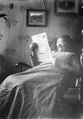 Sitter i gunsgstolen och läser.                    Tidsomfånget är 1900 - 1940