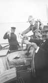 John Bauer och tre andra män i en fiskebåt på havet, håller upp fångsten, makrill.