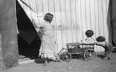 Tre barn leker med en vagn/skrinda. Familjen Taikons läger i Johanneshov, södra Stockholm.
