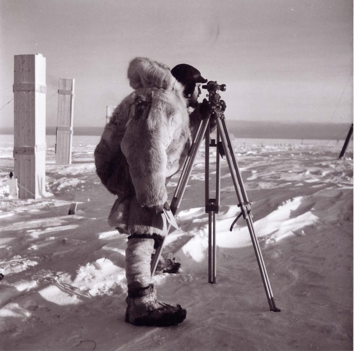 Stig Hallgren, "Charles Swithinbank med teodoliten på taket till Maudheim", Antarktis. Maudheim är den översnöade övervintringsstationen.