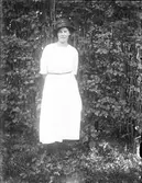 Kvinna i ljus klänning och hatt.