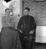 Kvinna och man vid kakelugn.