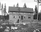 Familj utanför nybyggt hus.