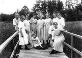 Tio flickor samlade på en träbro eller träbrygga.