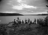 Vy med en grupp människor vid stranden, okänd plats.