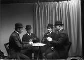 Fyra män spelar kort.