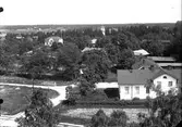 Vy över bostadsområde, Bergby. Längst fram till höger Bergby vita skola och bakom den gamla skolan. Den vita villan till vänster byggdes av Knut Persson och köptes av kommunen vid konkurs i början av 1930-talet och användes sedan som bostad åt bankkamrer Fasén och till kommunalhus.