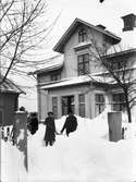 Jöns Wilander och dottern Anna Sofia skottar snö framför huset på Kvistholmsvägen i Norrsundet. Hustrun Sofia står till vänster.