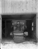 En bilmekaniker ovanpå en hög av bildäck i ett garage.