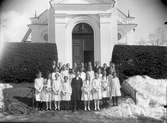 Gruppfoto av konfirmander 1927 framför kyrkan med Komminister Berglund.