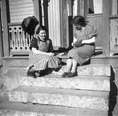 Två kvinnor på trappan den ene stoppar strumpor
