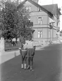 Kurt Persson och Bertil Persson. (Ev. Sture Olsson). Café- och Bankhuset i bakgrunden. Stationsgatan, Kilafors.
