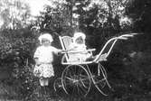 Barnporträtt. Två barn, det ena i barnvagn.