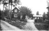 Huset är Lenninge 6:32. På trappan Per Larsson, född 1871, vid staketet till höger Herman Larsson, född 1896. Flickan med cykel kan vara Anna, född 1904.