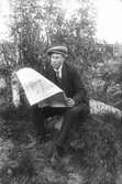 Mannen som läser tidningen är Herman Eriksson, född 1898, Lenninge 5:11.