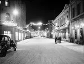 Drottninggatan, 1937. En stämningsfylld bild från Drottninggatan i slutet av 1930-talet. Juldekorationerna har satts upp och bjuder in till julhandel. Fotografen står med ryggen mot Centralplan. Närmast på höger sida ligger Eric Börjesons järnhandel och på vänstra sidan Lindbergs färghandel. 8 december 1937. (Bilden fanns med på utställningen år 2000).
