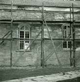 Böda kyrka under restaureringen 1942. Parti av långhusets norra vägg med korsarmens nordfasad. Under den nedknackade putsen syns det medeltida murverket med en igensatt portal.