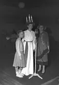 Mary Forslund, Gävle Lucia 1949. Hon är 21 år och handhar arkivet hos A/B Carl Larssons fotografiska atelier Tärnorna är Margareta Svensson, Harriet Jansson, Ulla Persson och Marianne Lundin. Luciatåget startar från Brandstation och går Nygatan - N. Skeppargatan - Drottninggatan - Stora Esplanadgatan och åter till Brandstationen. Soaré på teatern som arrangerat av köpmanna- och hantverkarungdomen i Gävle, leds av Macce Kjellin, kröntes Lucian med smycket av direktör Gösta Nygren, Furuvik. Lucia tävlingen arrangerades av Norrlands-Posten.

