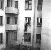 Två män vid och på stege vid flerbostadshus. Gävle den 19 september 1948.