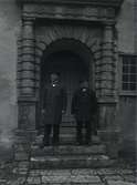 Två män i porten till slottet.