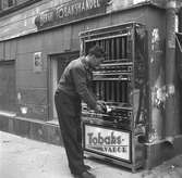 Bergii tobakshandel, Norra Kungsgatan. Tobaksautomat. Maj 1949.
Tobakshandeln låg i Rettigska huset och hade ingången från Södra Kungsgatan 1 med automaten runt hörnet på Södra Strandgatan.