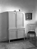 Vitrinskåp, stol, tavla och en matta. Den 18 oktober. Ahrnebergs