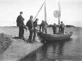 John Bauer och några män står på klipphällen och ser på när segelbåten lägger ut.