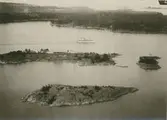 Flygfoto över ön Skansholmen vid farleden in till Västervik. Huset på ön är klubbhus för WSS (Westerviks SegelSällskap). Klubbhuset byggdes 1916 efter ritningar av arkitekt Axel J Sjögren.