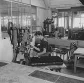 Folke Berg sitter vid maskinen och arbetar, på Huskvarna Borstfabrik.