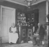 Ett äldre par som sitter intill ett skåp.