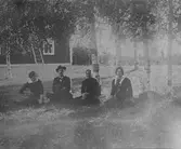 Sällskap som sitter i gräset utomhus.