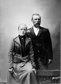 Ett par, man och kvinna, uppställda för fotografering.