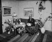 Man omgiven av blommor i bostadsmiljö, Östhammar, Uppland