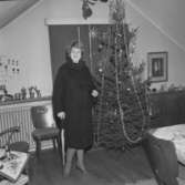 Rumsinteriör, en kvinna vid julgranen.Plutt