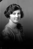 Ateljébild på en kvinna i halsband och klänning. Enligt Walter Olsons journal är bilden beställd av fröken L Dahlin.