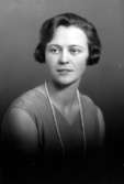 Ateljébild på en kvinna i halsband och klänning. Enligt Walter Olsons journal är bilden beställd av Ingrid Svensson.