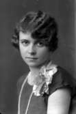 Ateljébild på en kvinna med blomma och pärlhalsband. Enligt Walter Olsons journal är bilden beställd av Inga Lisa undquist.