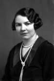 Ateljébild på en kvinna med pärlhalsband. Enligt Walter Olsons journal är bilden beställd av fröken A Eklund.