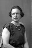 Ateljébild på en kvinna i pärlhalsband. Enligt Walter Olsons journal är bilden beställd av fru H Kindblom.