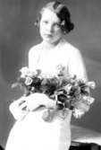 Ateljébild på en kvinna med en blombukett. Enligt Walter Olsons journal är bilden beställd av Anna-Lisa Bäckström.