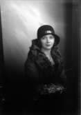 Ateljébild på en kvinna i hatt och i kappa med pläskrage. Beställare till bilden: Fröken Åström ifrån Kalmar.