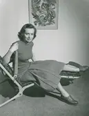 Modell i veckad kjol och jumper sitter i en 