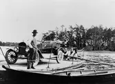 Södra Färjsundet med färjkarlen Per Olov Pettersson i förgrunden 1924. Färjan rors med åror. 
Bilen med registreringsnummer X1311 är en 1921 T-Ford som 1921 ägdes av A V Örberg i Norrsundet och som 1923 ägdes av L A Larsson Hedesunda.