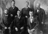 Johan Axel Hullander är mannen i mitten i övre raden på bilden. Mannen i mitten, understa raden är Johan Adam Ostheim. Foto förmodligen från 1880-talet i Gävle. Hullander var född 1863 i Strömsbro och utvandrade till Australien där han bl.a. arbetade vid gasverket i Mellbourne.