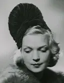 Modell i hög hatt, utan brätte. Draperad sammet.