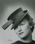 Modell i hatt med kulle och brätte, hattband med utstående slut.