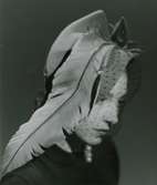 Porträtt av modell i grå filthatt med fjäder och flor, av Jacques Fath.