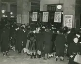 Realisation på Nordiska kompaniet. Trängsel kring varustånd med tyger. Text med blyerts på baksidan: Realisation (bild utan årtal).