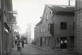 Ågatan vid Hantverkaregatan. Två servitriser står i dörren till lunchserveringen i hörnet Ågatan/Hantverkaregatan.
Herman Johanson kopparslagare till vänster i bild.